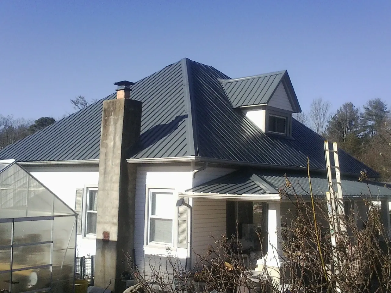 Dark blue standing seam metal roof on a white farmhouse with dormer — Slate & Tile Roof Repair by Roofing Brothers in Williamsfield