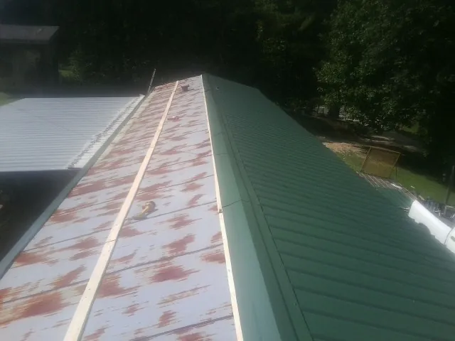 Old rusted panels beside newly installed green metal roofing — Wind Damage Roof Repair by Roofing Brothers in Williamsfield